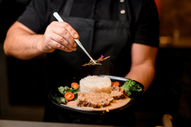 男士手持一盘一盘的碟子，用迷迭香树枝精心装饰图片下载