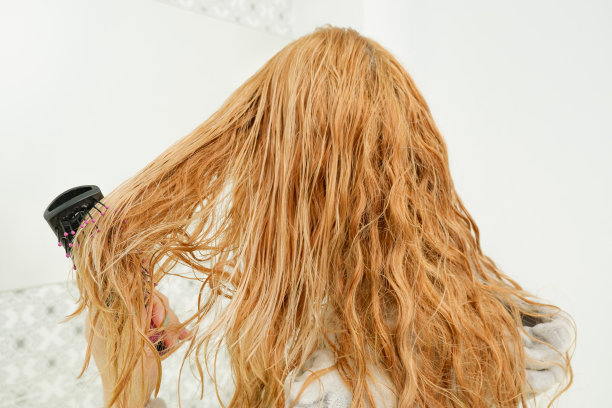 一个女人洗完澡后梳理她那湿漉漉乱糟糟的头发。从后面看图片下载