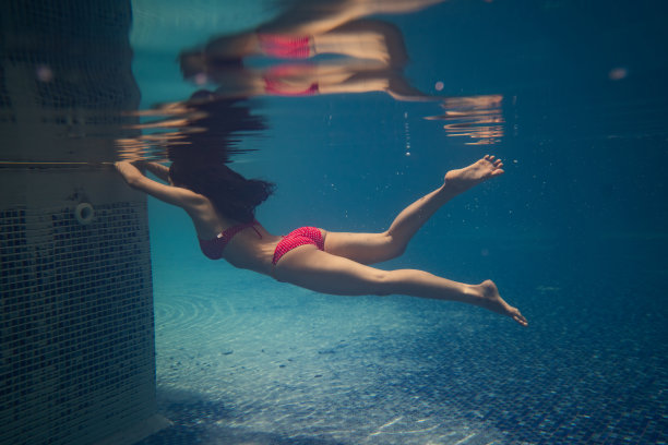 在泳池边，亚洲女性正在跳水。她穿着比基尼。图片下载