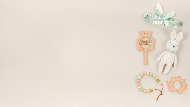 婴儿玩具和配件的背景拷贝空间。可爱的木制牙齿，手工编织的兔子，婴儿珠和淡棕色旗帜上的发带。图片下载