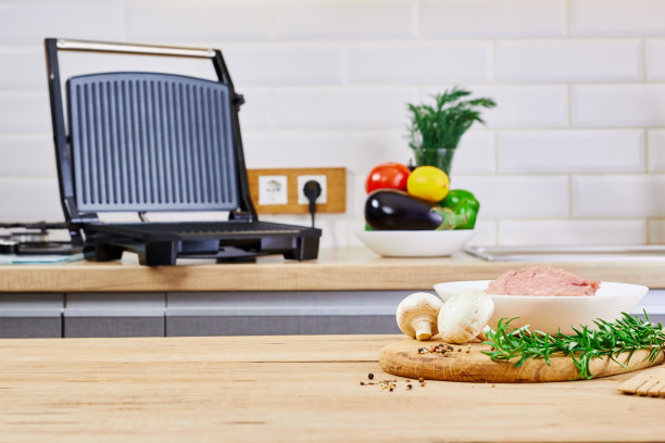 在厨房内部准备烧烤。电烤架烧烤和肉类在厨房的桌子上。图片下载