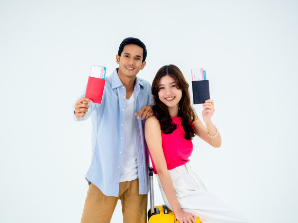 一对旅行者在快乐的假期。暑假蜜月概念。微笑的亚洲夫妇持有和出示护照，准备旅行，年轻的女人和男人的行李隔离在白色背景。图片下载