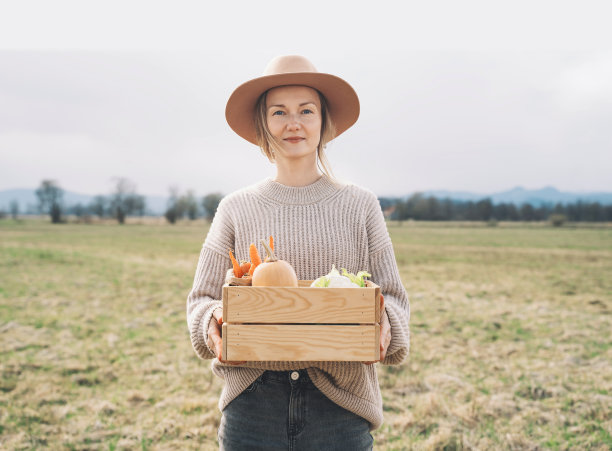 妇女与当地有机食品的农田地区。在当地农贸市场的户外，顾客或农民带着一箱蔬菜。不使用塑料的可持续购物。中小企业的概念。图片下载