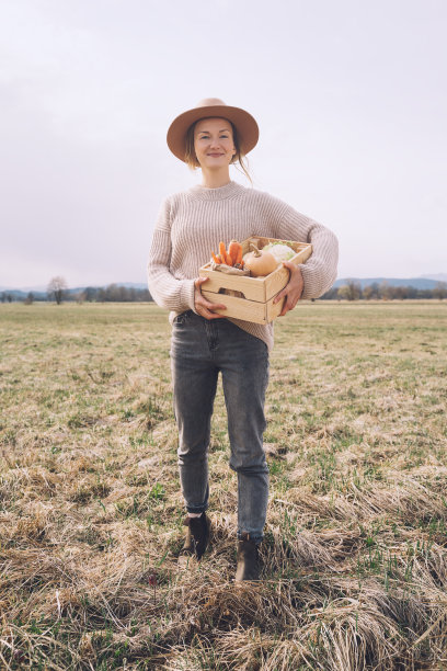妇女与当地有机食品的农田地区。在当地农贸市场的户外，顾客或农民带着一箱蔬菜。不使用塑料的可持续购物。中小企业的概念。图片下载