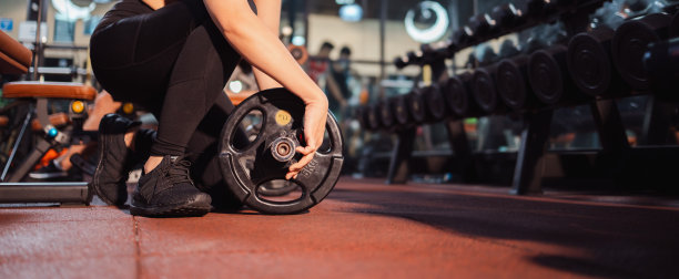 年轻女子与杠铃屈肌肉在健身房运动，健美，生活方式，和人的概念图片下载