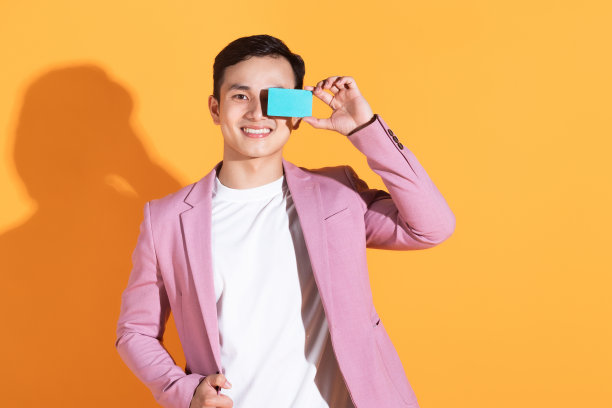 图片上的年轻亚洲男子手持银行卡，背景是atm卡图片下载