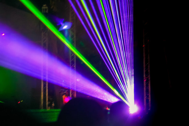 紫色激光氖光束。在街头音乐节上观看激光表演的人群。图片下载