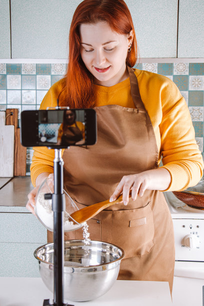 现代女性博客为美食博客直播。年轻女子在家里厨房做饭。图片下载