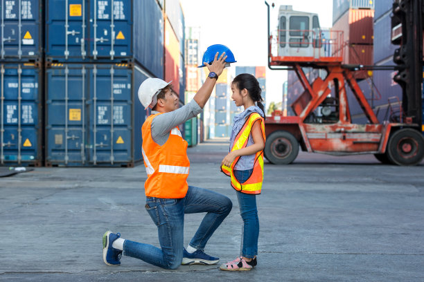 货柜装卸现场，父亲和小女儿戴着安全帽。企业继承人的概念。快乐父女戴安全帽工作现场。企业继承人的概念。图片下载