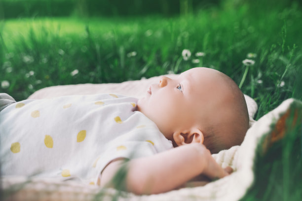 夏天的户外，可爱快乐的宝宝躺在绿油油的草地上。3个月大的赤脚婴儿在大自然中。生态可持续生活方式的家庭和儿童概念。图片下载