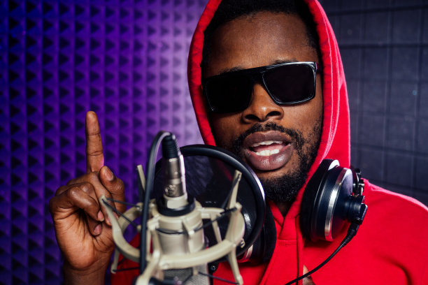 美国黑人男子戴着耳机，戴着帽子和兜帽墨镜录制嘻哈歌曲。图片下载