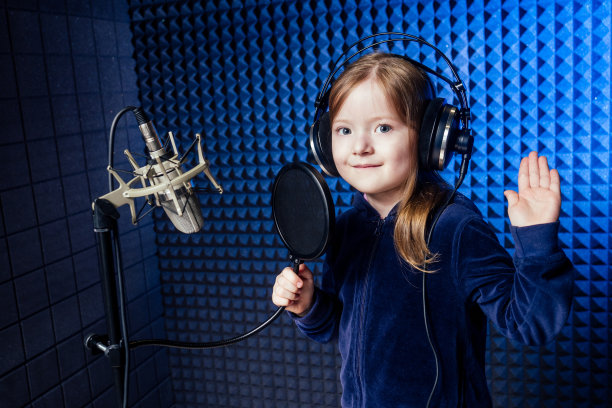 女明星歌手艺术家穿着黑色衬衫，戴着耳机，用麦克风录制新歌。图片下载