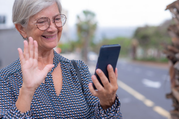 年长自信的白人女商人肖像站在户外与城市的背景使用手机在视频会议图片下载