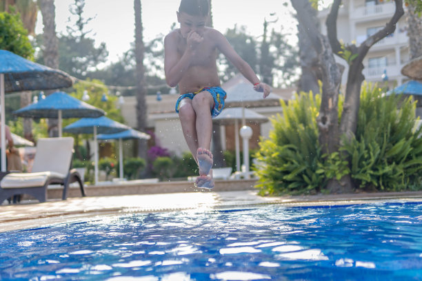 你好夏天，男孩在游泳池里跳图片下载