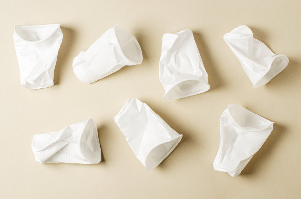 一次性白色塑料餐具，米色背景。自然污染的概念图片下载