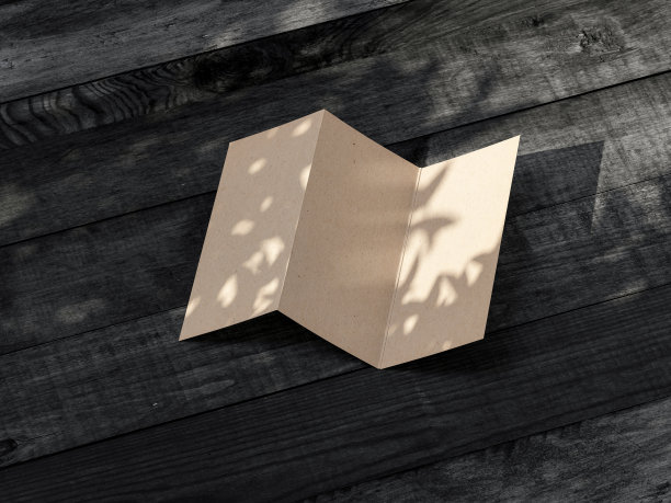 牛皮纸三折传单邀请模型在户外的黑色木桌上图片下载