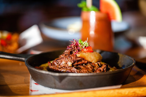 在豪华餐厅的木桌上，用平底锅煎熟的鲜肉。烤牛肉配蔬菜和冷饮。美食食品图片下载