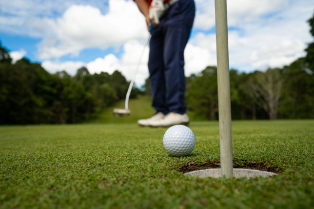 高尔夫球手把球在草地高尔夫球，镜头耀斑在夕阳黄昏时间。图片下载