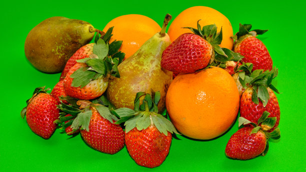 草莓、梨子和橘子在绿色的背景上。图片下载