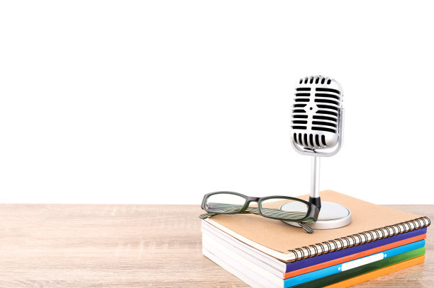 教育教学理念:复古的麦克风与许多书和眼镜放在木制桌子孤立在白色背景。图片下载