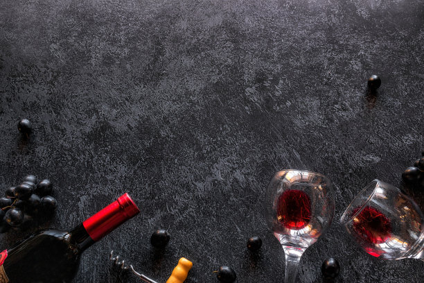 葡萄酒的瓶子，酒杯与红酒和葡萄在黑色的背景与文字的空间图片下载