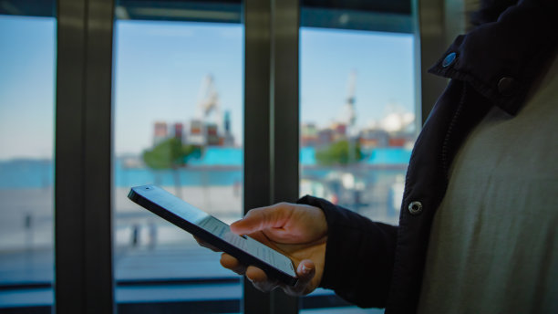 一名男子站在码头办公室使用手机图片下载