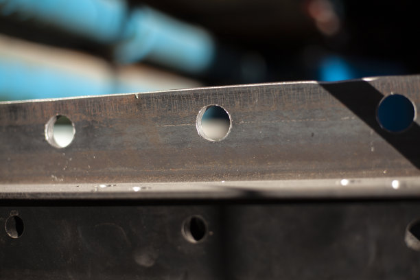 在钢材上钻孔。金属空白。钢型材在车间用钻头钻孔。铁产品。图片下载