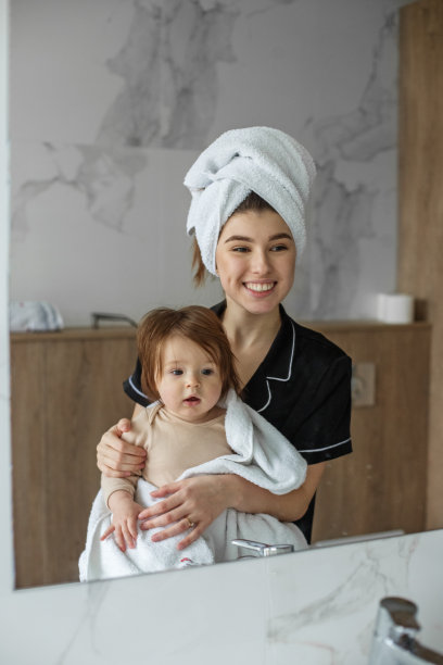 浴室淋浴后，年轻母亲带着用毛巾裹着的婴儿。卫生和清洁的概念。图片下载