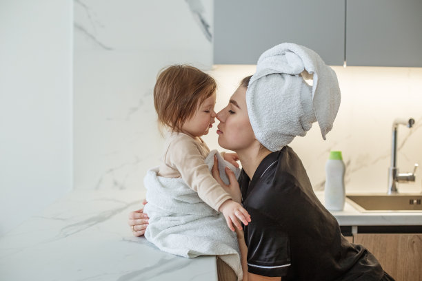 美丽的年轻母亲是有乐趣的婴儿蹒跚学步的女孩。保健和母亲。拥抱和亲吻。图片下载