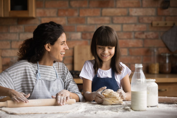 快乐的妈妈教可爱的女儿女孩烘焙，滚动图片下载