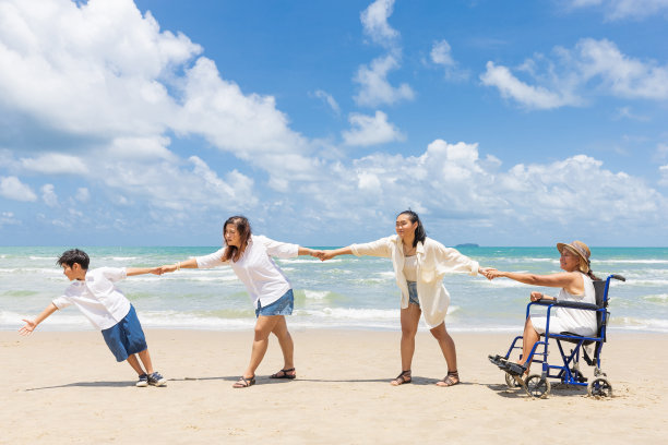 坐在轮椅上的女人和家人在海滩上握手图片下载