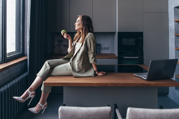 休息期间，一个女人坐在厨房里拿着一个苹果图片下载