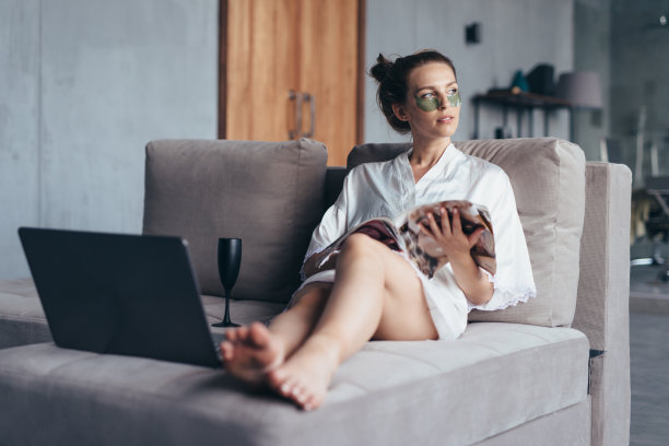 一位妇女在家里用眼镜看一本光滑的杂志，正在做返老还老的手术图片下载