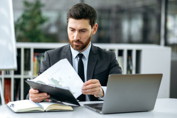 聪明自信的白人大胡子商人，公司的ceo，最高经理，财务专家，坐在现代办公室，集中研究财务文件，计划发展业务战略图片下载