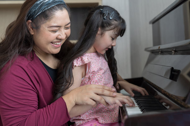 女孩在家里和女老师一起学钢琴。亚洲钢琴家老师在学校教女孩孩子弹钢琴。图片下载