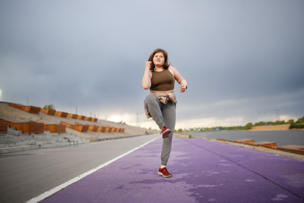 欧洲超重少女沿着城市堤岸在跑步机上慢跑，超重而积极的青少年生活方式图片下载