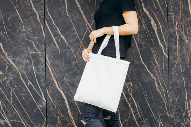年轻的亚洲模特女孩穿着t恤在街上拿着白色的环保袋，模拟图片下载