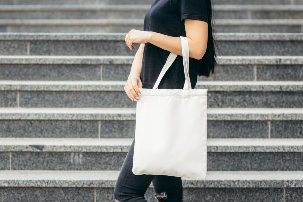 年轻的亚洲模特女孩穿着t恤在街上拿着白色的环保袋，模拟图片下载