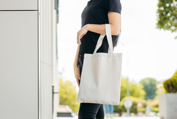 年轻的亚洲模特女孩穿着t恤在街上拿着白色的环保袋，模拟图片下载