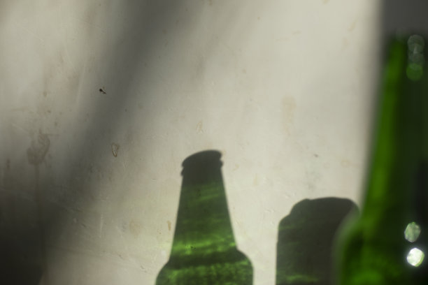 用一瓶啤酒照亮墙壁。绿色的玻璃和墙上的阴影。图片下载