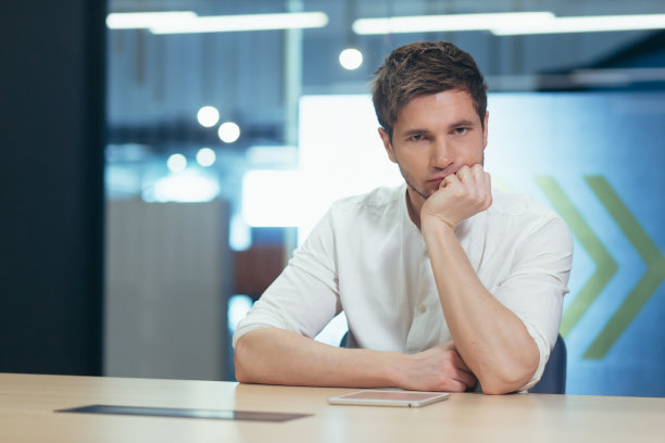 一个年轻男学生的肖像。认真备考，在线学习，远程学习。手捧着笔记本电脑坐在桌旁，疲惫不堪图片下载