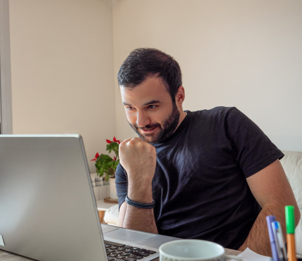 兴奋的商人在家用笔记本电脑工作，享受他的利润图片下载