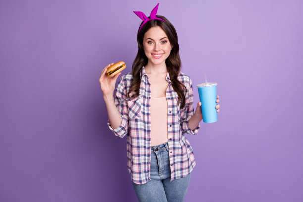 照片肖像的女人拿着芝士汉堡和可乐在手中孤立在生动的紫罗兰色背景图片下载