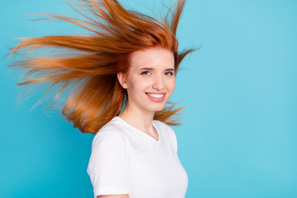 年轻女孩的侧面照片快乐积极的微笑飞空气洗发液体积孤立在蓝色的背景图片下载
