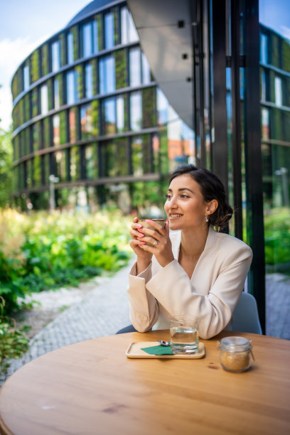 年轻的商业女性持有和喝咖啡在街头咖啡馆在城市。在布拉格街头等待客户的美丽女工肖像图片下载