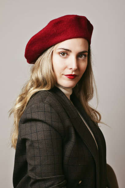 工作室肖像的金发女孩长头发戴红色贝雷帽，红色的嘴唇和西装外套。图片下载