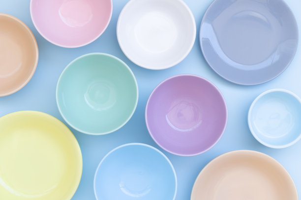 一套彩色陶瓷碗和盘子的蓝色背景。前视图。图片下载