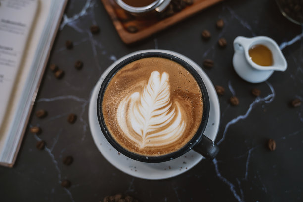 背景横幅杯蜂蜜卡布奇诺与拉花艺术在木制俯视图，平铺。黑色陶瓷杯拿铁咖啡黑色复古风格。图片下载