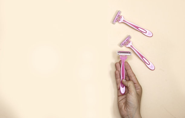 特写手持粉色一次性剃须刀的女人。脱毛与护肤理念图片下载