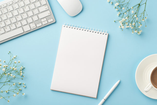 经营理念。工作空间的俯视图照片，键盘，电脑，鼠标，打开提醒笔，咖啡杯，茶碟和白色的石膏花，孤立的淡蓝色背景与空白图片下载